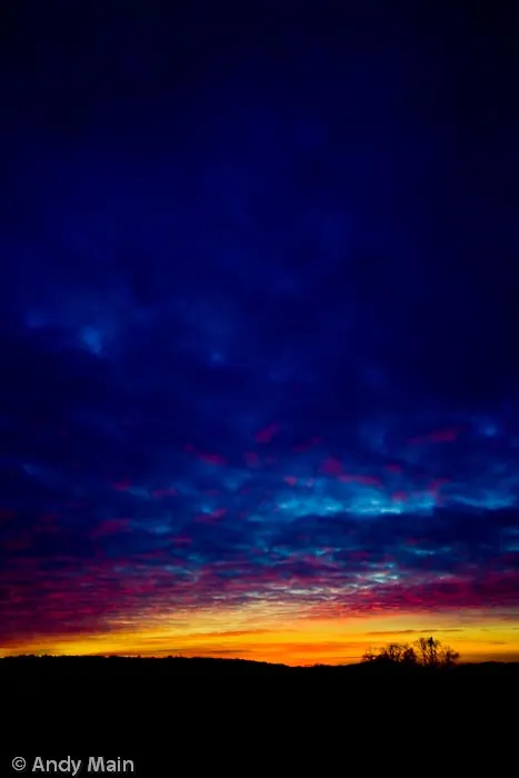 The glorious under lit sunset fades into the dark blue clouds.